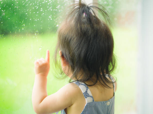 istock baby girl looking outside rainning 807834106