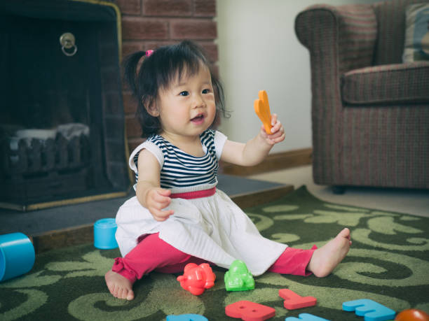 istock baby girl playing alphabet blocks at home 807834176