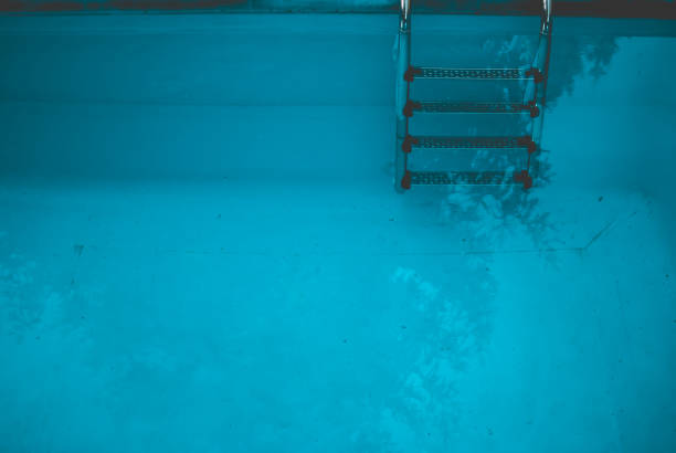 istock Swimming pool ladder and dark blue dirty water. 807844874