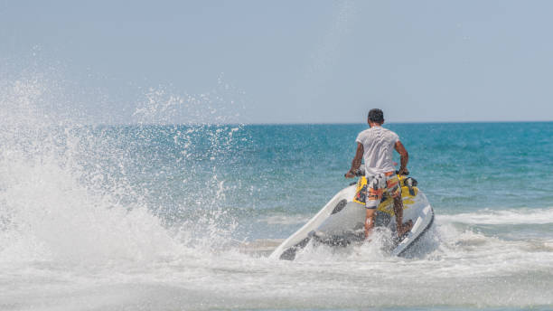 młodzi mężczyźni przelatujący po morzu karaibskim na skuterze wodnym - wake jet boat water water sport zdjęcia i obrazy z banku zdjęć