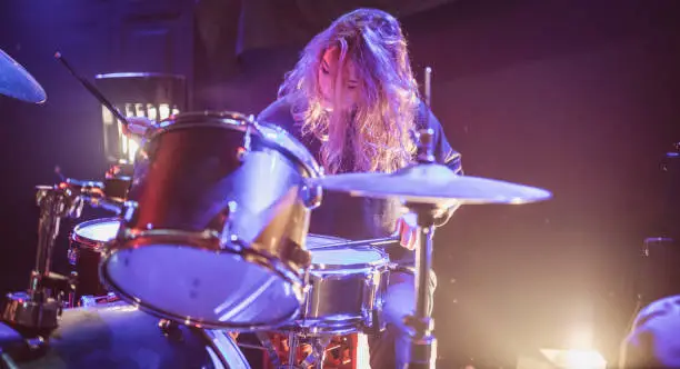 Woman drummer playing drums on stage in the club