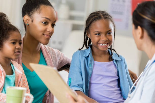 istock Happy elementary age girl talks with pediatrician 807902932