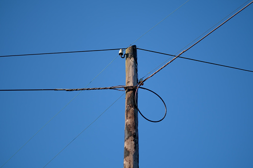Old low tension electrical pole on blue sky