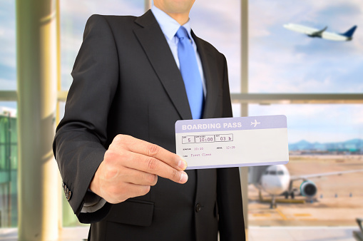 Businessman holding boarding pass, indoor at airport departure lounge