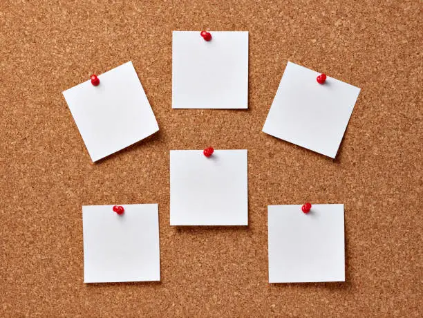 close up of note papers on a corkboard