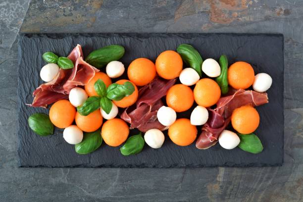 istock Salad with cantaloupe, mozzarella, prosciutto and basil on slate server 807953428