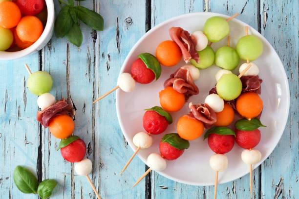 Plate of summer fruit skewers on a rustic blue wood background