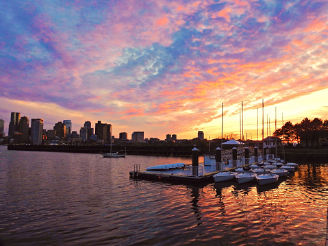 Sailboats at rest fronting Boston's Cityscape at sunset.