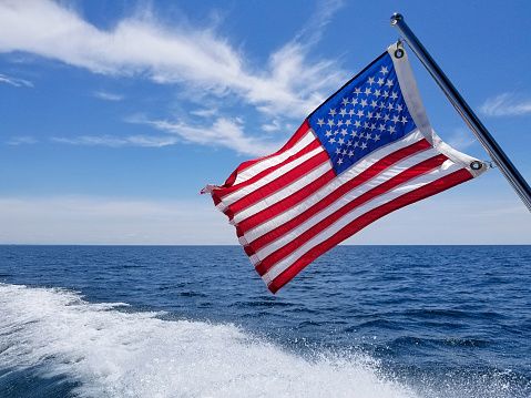 American flag on boat pole with boating wake on Lake Michigan