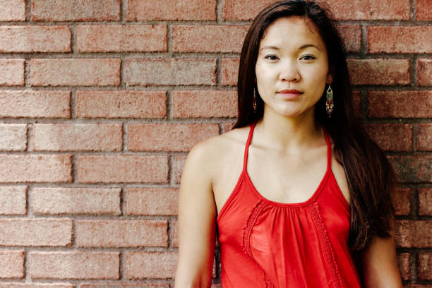 istock Asian woman standing against brick wall 808022558