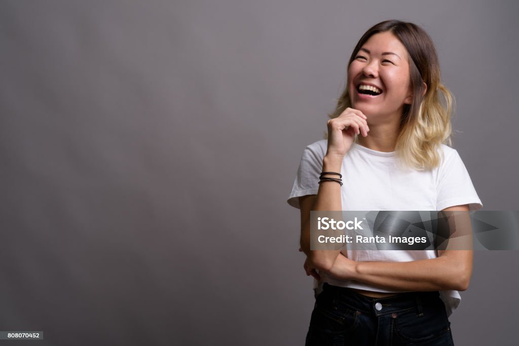 Studio shot of young Asian woman wearing white shirt against gray background Studio shot of young Asian woman wearing white shirt against gray background horizontal shot One Woman Only Stock Photo