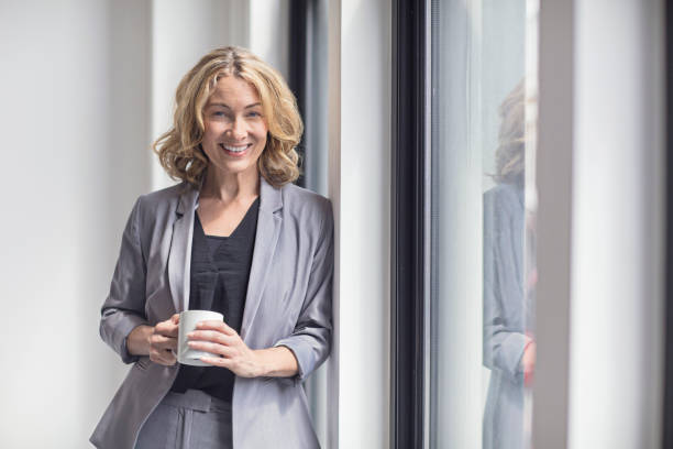 istock Happy businesswoman holding coffee mug by window 808093592