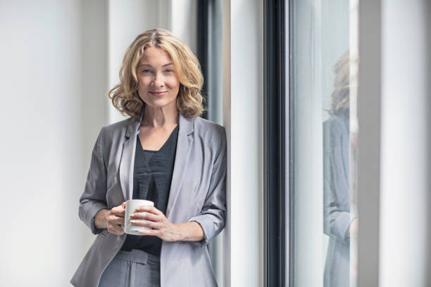 Smiling businesswoman holding coffee mug by window