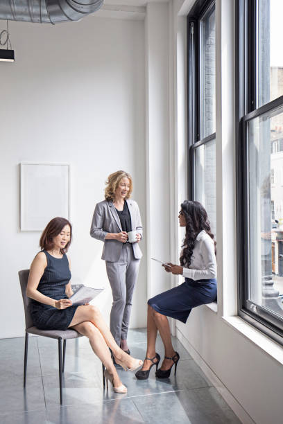 istock Businesswomen discussing by window in office 808093606