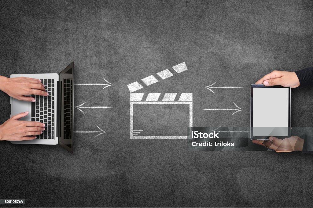 Concept of video file sharing on blackboard Businesswoman using laptop and digital tablet with video file icon on blackboard Movie Stock Photo