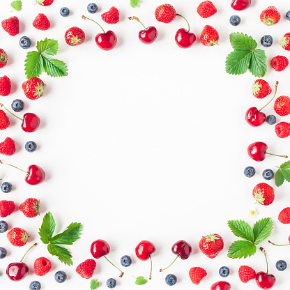 A number of strawberries, whole and sliced, on a wooden tray against a red background.