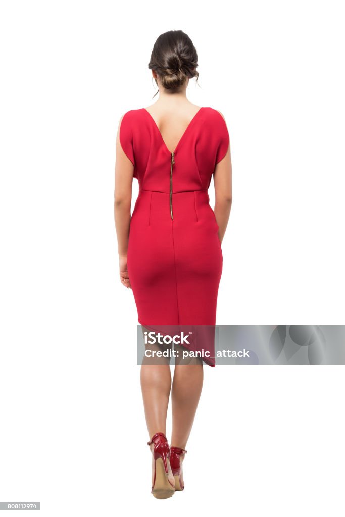 Rear view of elegant woman with bun hairstyle in red evening dress walking away. Rear view of elegant woman with bun hairstyle in red evening dress walking away. Full body length portrait isolated on white studio background. Rear View Stock Photo