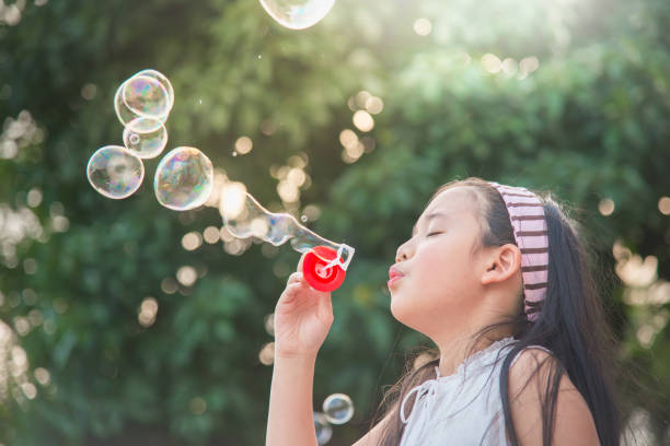 istock Cute asian girl is blowing a soap bubble 808119148