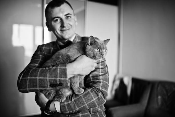 Handsome groom posing with a little cute kitten in his room.