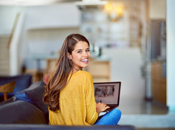 My blog is getting tons of traffic Portrait of an attractive young woman using a laptop while relaxing on the sofa at home looking over shoulder stock pictures, royalty-free photos & images