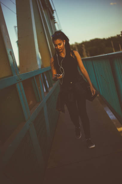 hermosa chica caminando y escuchando música en el puente - grand river audio fotografías e imágenes de stock