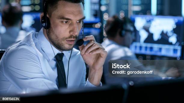 In Monitoring Room Technical Support Specialist Speaks Into Headset His Colleagues Are Working In The Background Stock Photo - Download Image Now