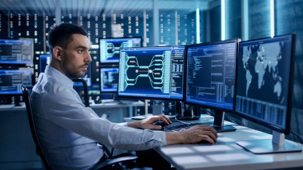 System Security Specialist Working at System Control Center. Room is Full of Screens Displaying Various Information. System Security Specialist Working at System Control Center. Room is Full of Screens Displaying Various Information. control room stock pictures, royalty-free photos & images
