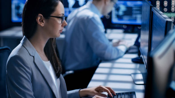 istock Female Engineer Controller Observes Working of the System. In the Background People Working and Monitors Show Various Information. 808157402