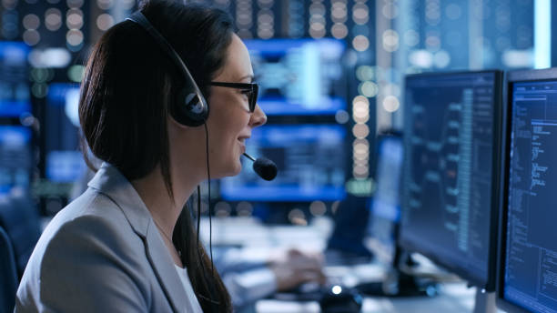 In the System Control Center Woman working in a Technical Support Team Gives Instructions with the Help of the Headsets. Possible Air Traffic/ Power Plant/ Security Room Theme. In the System Control Center Woman working in a Technical Support Team Gives Instructions with the Help of the Headsets. Possible Air Traffic/ Power Plant/ Security Room Theme. facilities protection services stock pictures, royalty-free photos & images