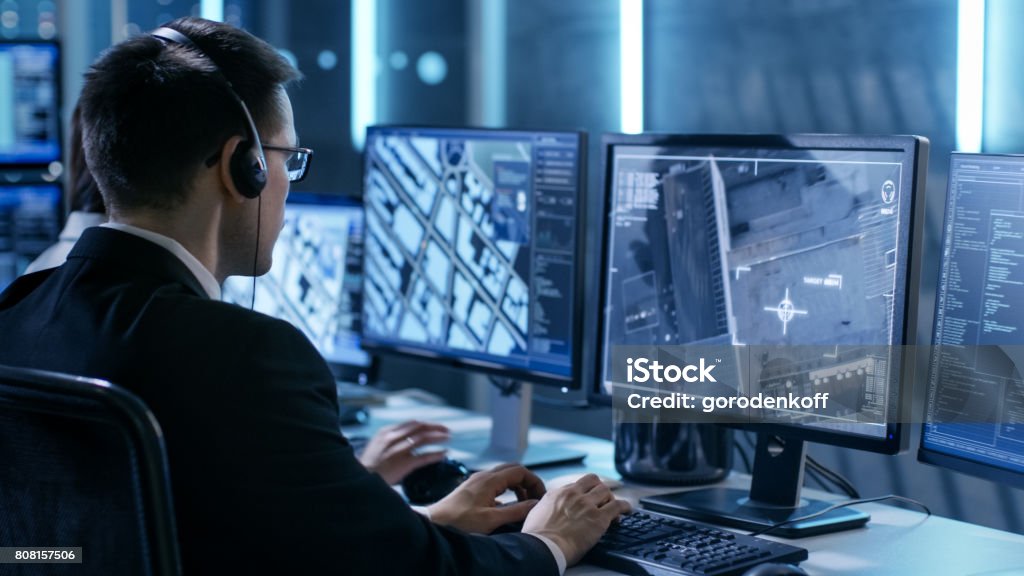 Government Agent is Tracking Fugitive with Her Computer in Big Monitoring Room Full of Computers with Animated Screens. Control Room Stock Photo