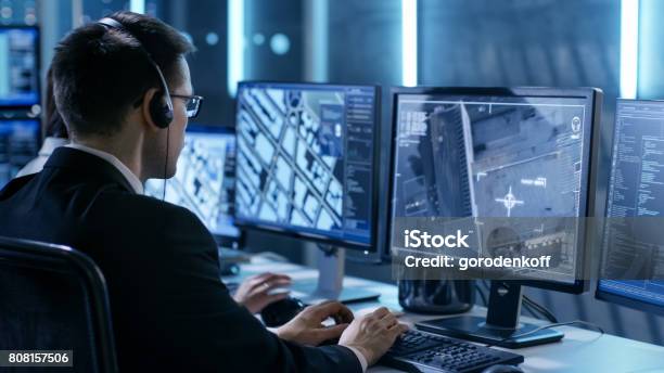 Government Agent Is Tracking Fugitive With Her Computer In Big Monitoring Room Full Of Computers With Animated Screens Stock Photo - Download Image Now