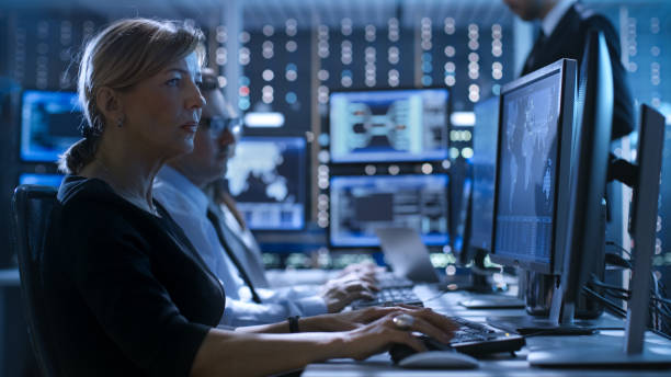 female government employee works in a monitoring room. in the background supervisor holds briefing. possibly government agency conducts investigation. - war armed forces military conflict imagens e fotografias de stock