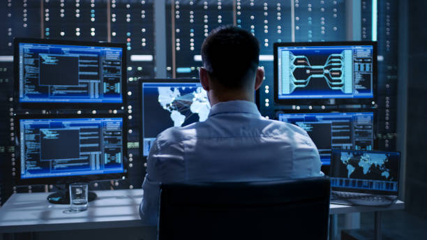 system security specialist working at system control center. room is full of screens displaying various information. - espião imagens e fotografias de stock
