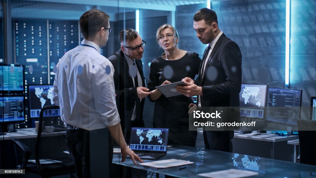 Team of Corporate Managers Having Meeting in Monitoring Room. They're in State of the Art Facility. Computers have Animated Screens. Business Meeting Stock Photo