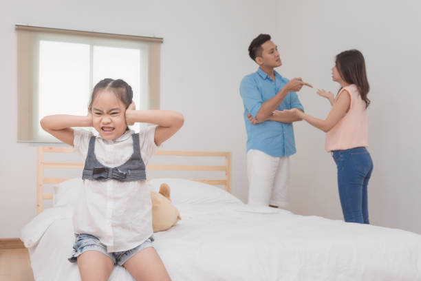 Asian little girl sad and closing her ears while parent quarrelling and fighting in bedroom Asian little girl sad and closing her ears while parent quarrelling and fighting in bedroom.Photo design for family problems and unhappy concept asian baby crying while mother scolding stock pictures, royalty-free photos & images