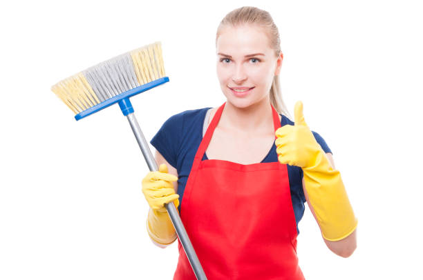 istock Attractive woman holding broom and smiling at camera 808219778