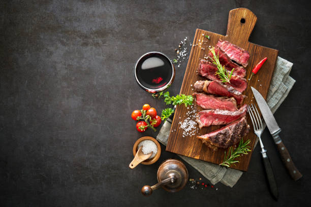 em fatias médias raro grelhado bife bife - rib eye steak beef cutting board meat - fotografias e filmes do acervo