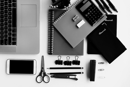 Solid black and white Top view of office supplies, smart phone and laptop