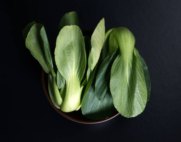 close up Fresh baby green bok choy in bowl on the  black background , overhead or top view shot