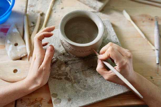 istock Artist paints a pattern on a clay pot 808405894