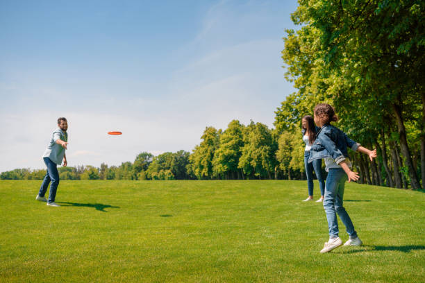 istock Happy parents with daughter playing with flying disk on green grass 808409948