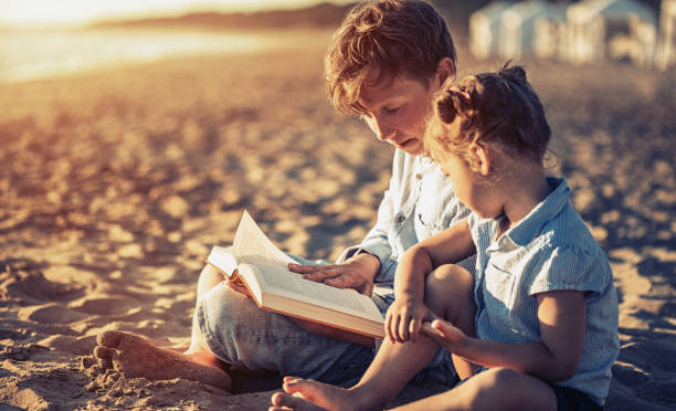 istock Children reading a book on beach at sunset 808422594