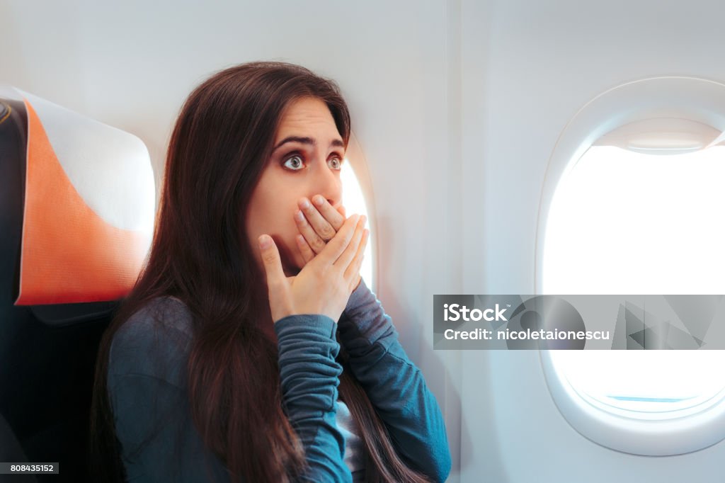 Woman Sitting By the Window on An Airplane Feeling Sick Aircraft passenger having a bad episode of motion sickness Airplane Stock Photo