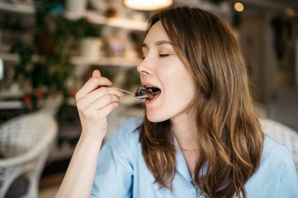 Woman eating a cake A young woman is eating a cake in a cozy cafe. She closed her eyes with pleasure dessert sweet food stock pictures, royalty-free photos & images