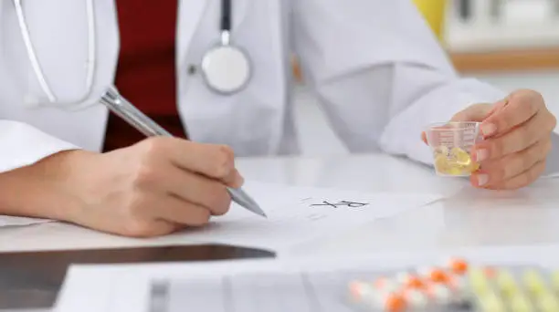 Female medicine doctor fills up prescription form to patient closeup. Panacea and life save, prescribe treatment, legal drug store, contraception concept.