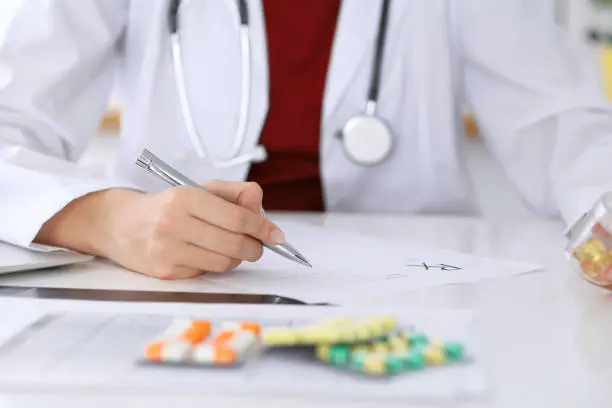 Female medicine doctor fills up prescription form to patient closeup. Panacea and life save, prescribe treatment, legal drug store, contraception concept.