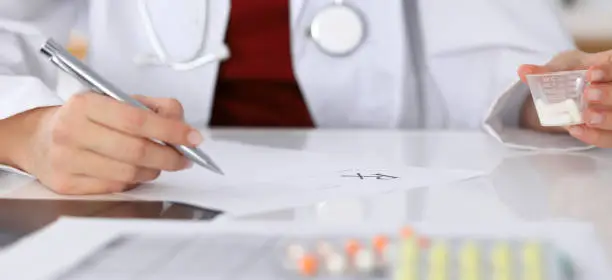 Female medicine doctor fills up prescription form to patient closeup. Panacea and life save, prescribe treatment, legal drug store, contraception concept.