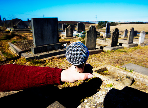 Microphone held to a tomb stone in a cemetary