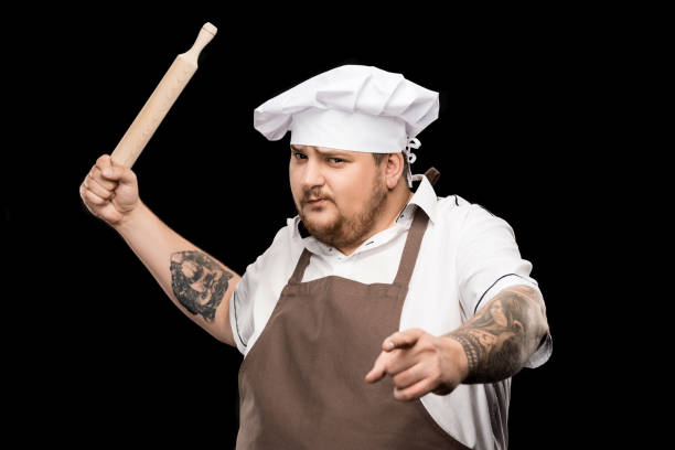 istock Serious professional chef holding rolling pin and pointing at camera 808517826