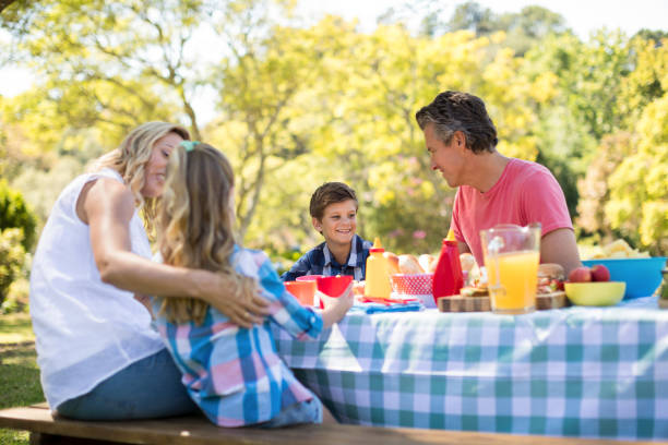 istock Happy family interacting with each other while having meal in park 808531950
